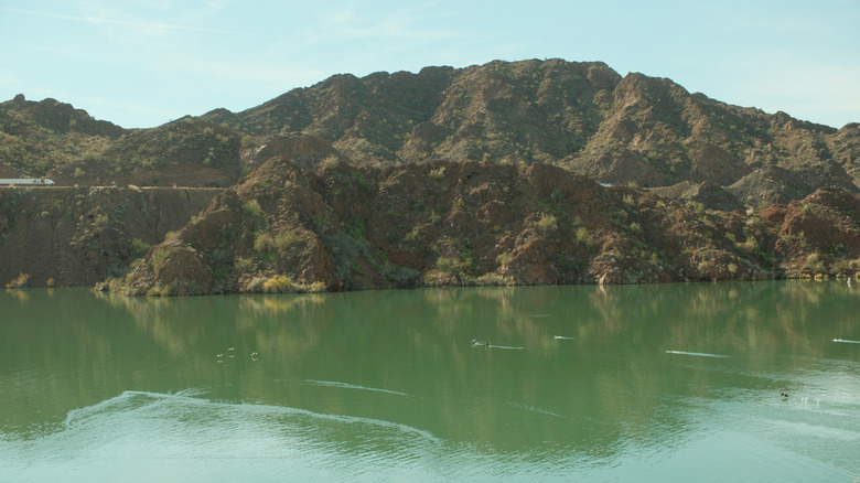 Green waters below a rugged desert mountain landscape