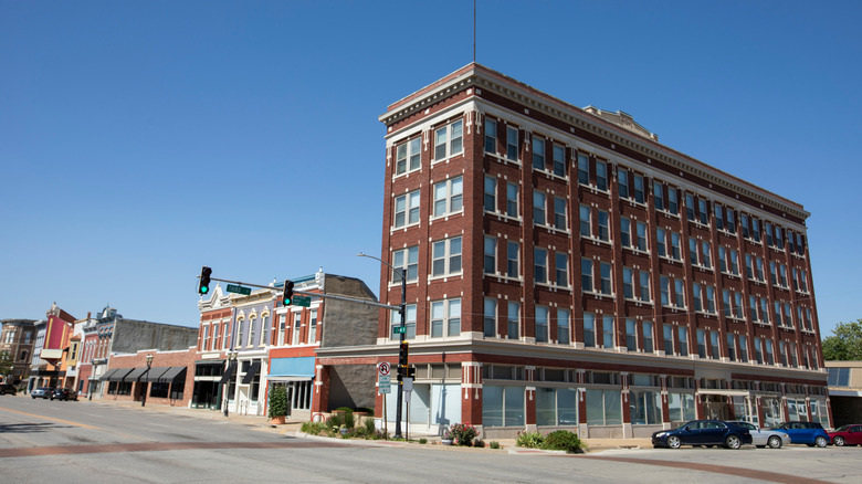 Downtown intersection in Ottawa, Kansas, dominated by a large multi-story red-brick building with historic storefronts extending along the adjacent street