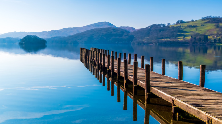 Wooden pier extending toward Coniston Water, Lake District National Park, England, with calm waters and a mountain backdrop