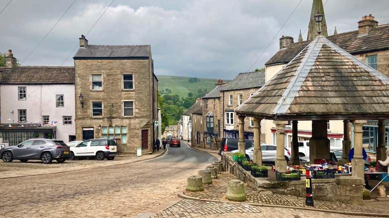 Stone townhouses and an old market pavilion in Alston, with hills in the background