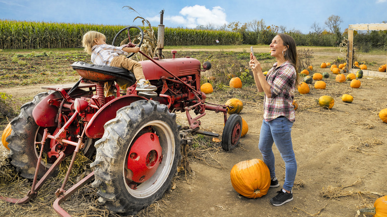 A mother and child with tractor and pumpkins