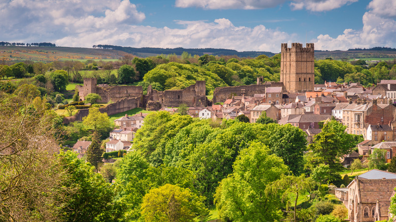 Stone buildings and castle of Richmond surrounded by green trees and cloudy blue sky