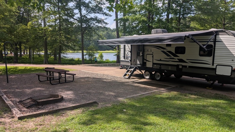 Trailer parked at a wooded lakeside campsite with a picnic table at the White Oak Lake State Park campground, Arkansas
