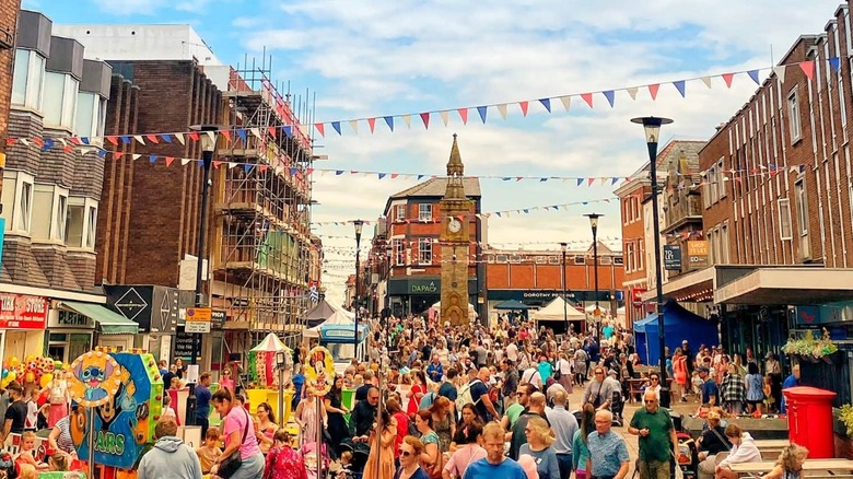Colorful crowd and historic buildings along with the Ormskirk Clock Tower in the background of the outdoor Ormskirk Gingerbread Festival