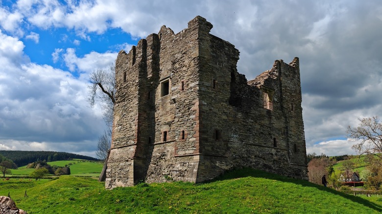 A sturdy castle ruin sits on a green meadow in Shropshire Hills