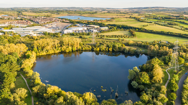 A small lake in the countryside just outside of Leighton Buzzard ringed with trees and country fields