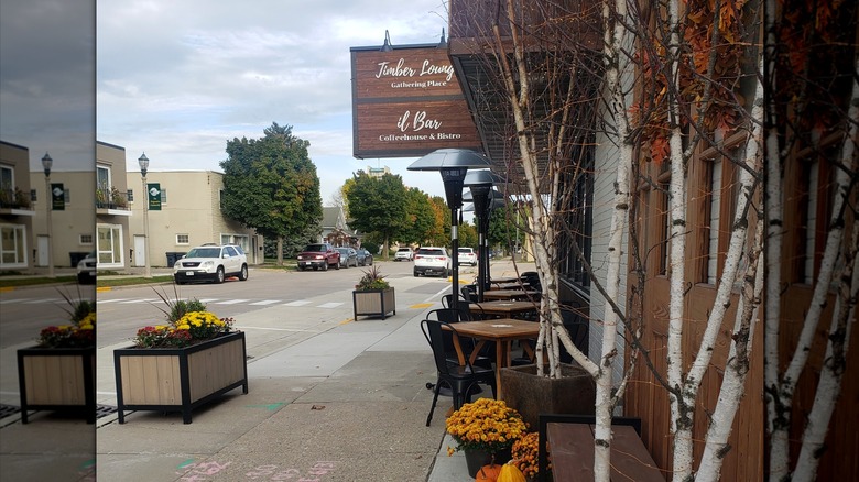 A downtown Kimberly street with il Bar Coffeehouse and tables on the street, with cars and trees in the background