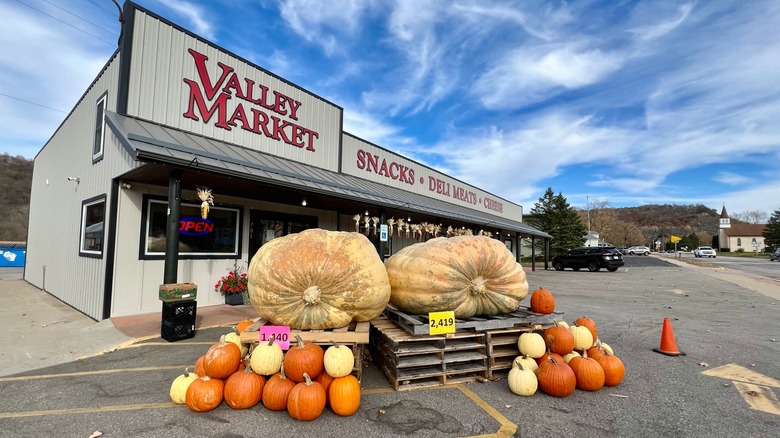In front of the Valley Market with large autumn pumpkins and the buildings of downtown in the distance