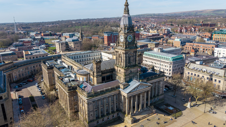 An aerial view of a Bolton's Neoclassical town hall, with its pillars, clock tower, steps, and plaza
