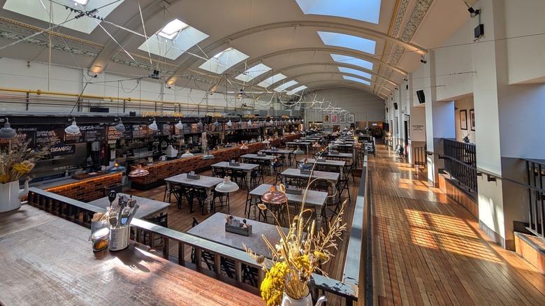Food stalls, tables, and chairs under an arching roof with skylights inside Picturedrome Macclesfield