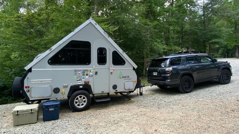 An a-frame camper and an SUV at a campground