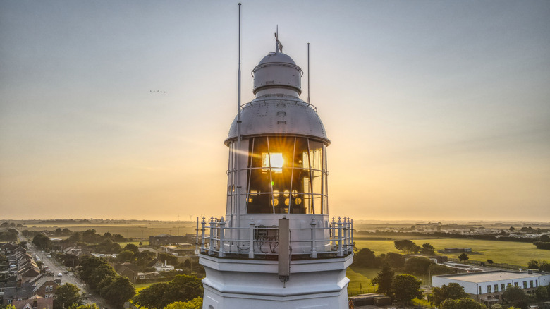 The top of Withernsea Light House with the sun setting over fields behind it