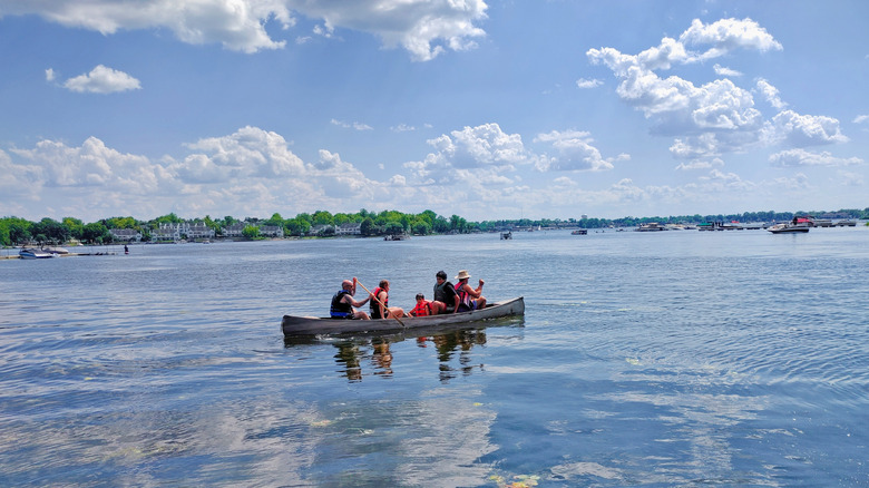 people paddling a canoe on Bangs Lake in Wauconda, Illinois with trees and houses in the distance