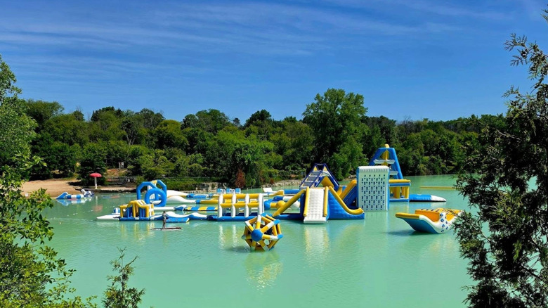 Aqua park floating in turquoise water surrounded by trees at Sheboygan Quarry Beach & Waterpark