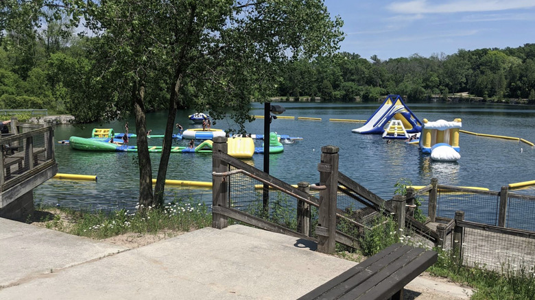 Concrete patio with stairs leading to water, aqua park, and beach at Sheboygan Quarry.