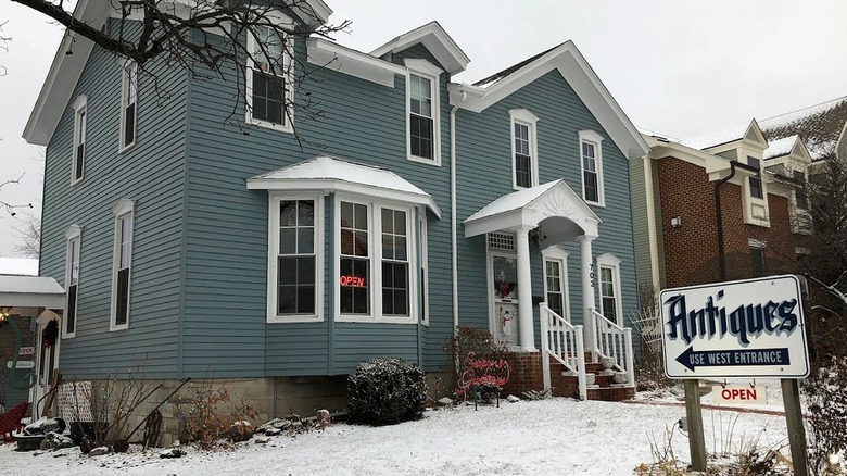 A blue timber house with white trim with a sign out front that says 