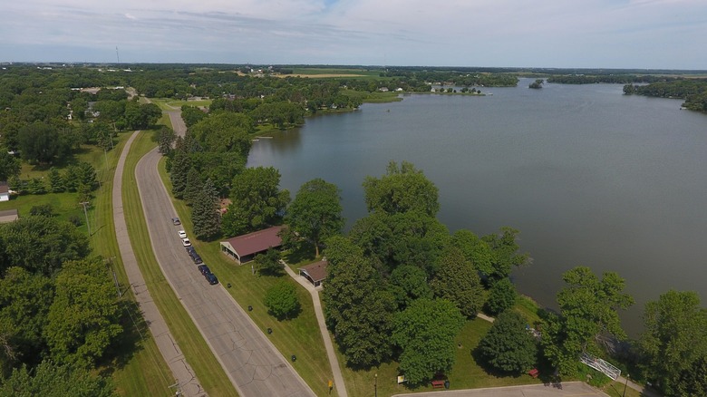 An aerial photo above Lake Sauk, lined with large green trees and a scattering of houses on an overcast summer day