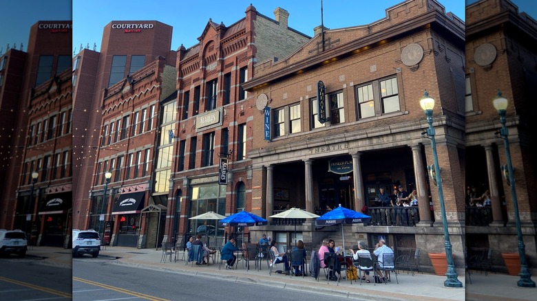 Dining tables on the street in front of a theatre in downtown St. Cloud, with the brick buildings showcasing the architecture