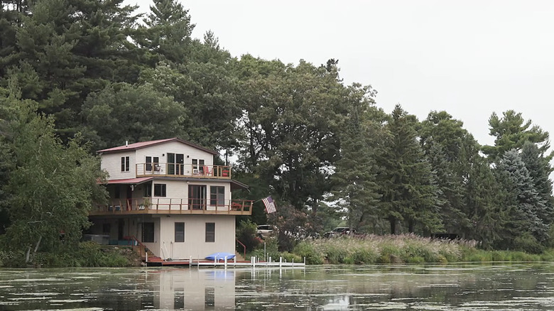 A three-story house nestled in trees and overlooking Lake Hallie