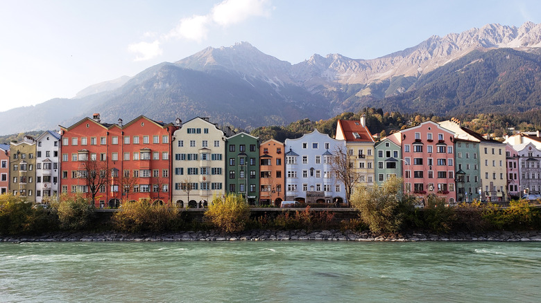 A row of colorful buildings along the base of the River Inn and Nordkette Mountains in Innsbruck, Austria