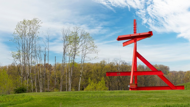 An abstract red metal sculpture on top of a hill at Storm King Art Center.