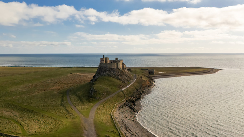 Castle silhouette on top of a hill overlooking the calm sea on a clear day