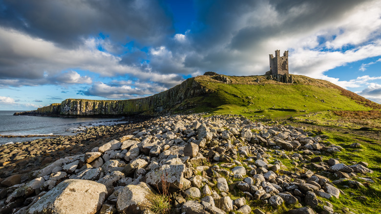 Dunstanburgh Castle ruins, on a hill above cliffs that plunge into the sea near Craster, Northumberland