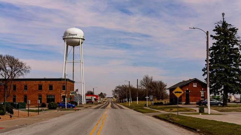 Road through Stuart, Iowa, lined by historic brick building and water tower