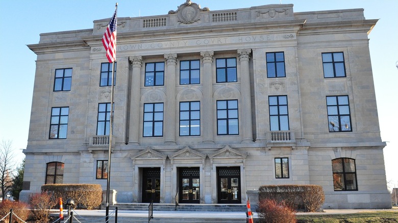 The stone facade of Brown County Court House in Hiawatha with shrubs and grass out front.
