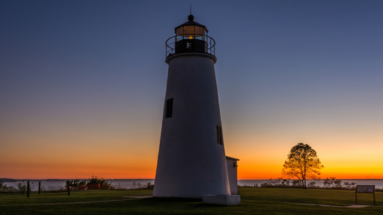 Turkey Point Lighthouse and the surrounding grass and water during a fiery sunset.
