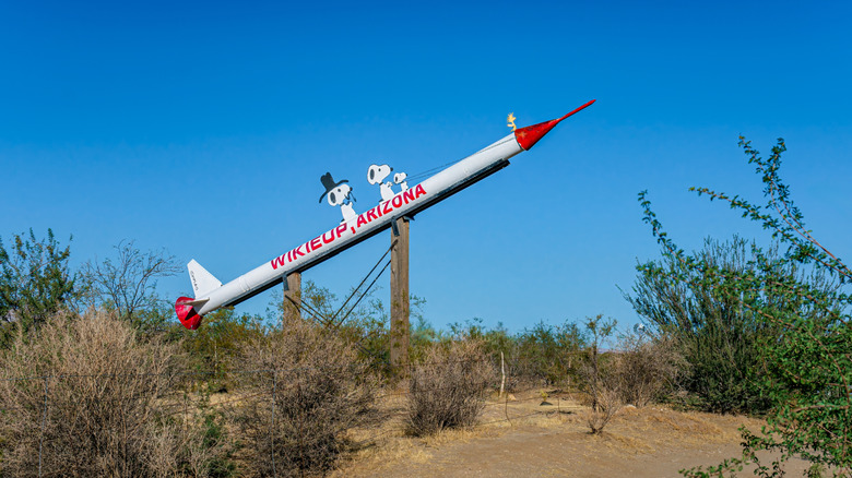 A large model rocket with Wikieup, Arizona written on its side being ridden by Snoopy, Woodstock and other Peanuts characters.