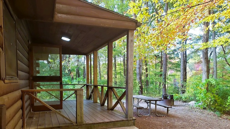 A rustic cabin with a picnic bench inside a wooded area at Moraine State Park in Pennsyvania.