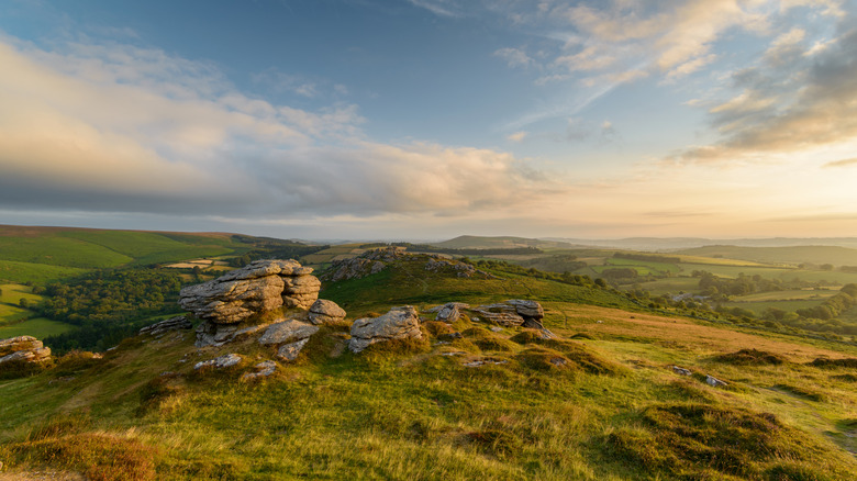 The view from atop Hound Tor in Dartmoor National Park, surrounded by green fields at sunrise