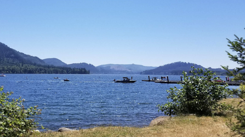 Wide shot of Yale Lake with boats on the water near a dock, mountains in background.