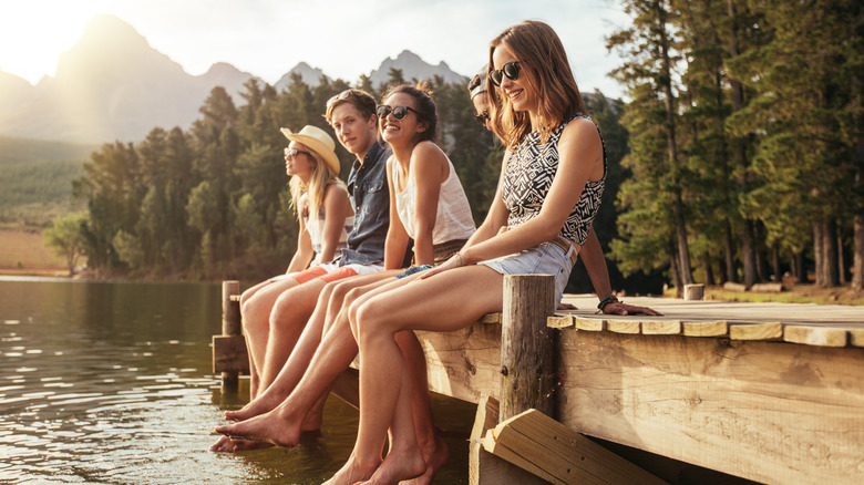 A group of young people sitting on a dock by the river
