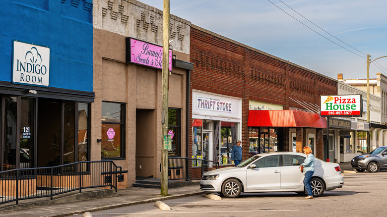 A couple of cars and people in front of a row of shops on a main road in Erwin, North Carolina