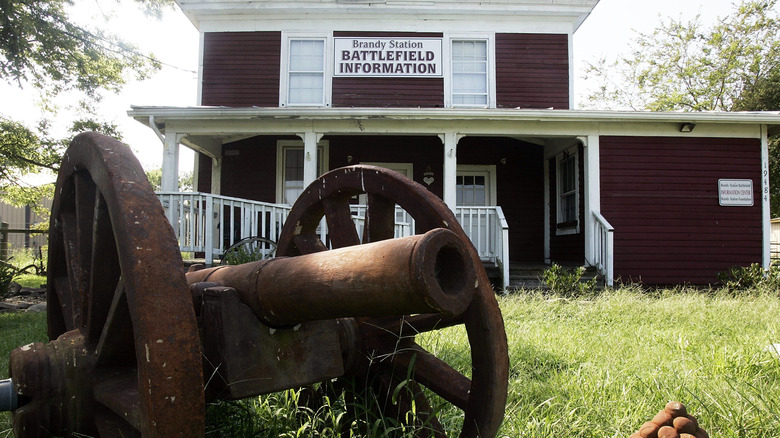 Brandy Station Graffiti House, a two-story home with dark brown walls and a rusty cannon in the foreground