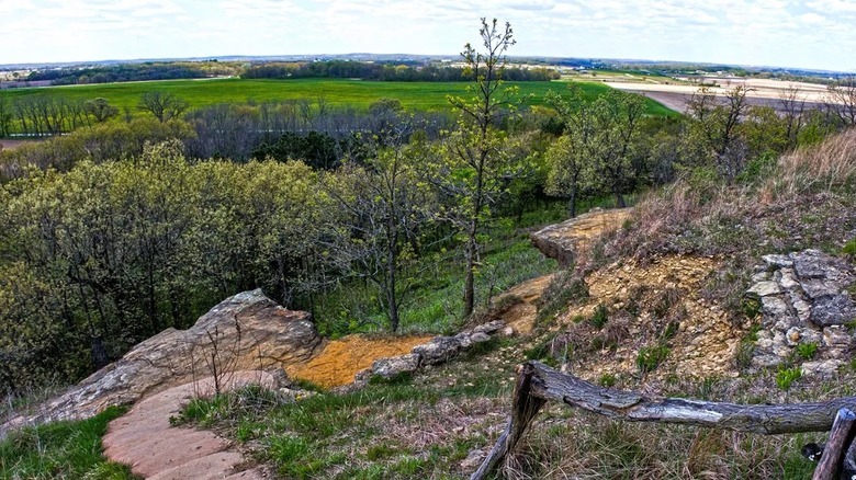 Expansive views of the countryside from a trail at Magnolia Bluff Park in Wisconsin, surrounded by a rocky landscape and trees.