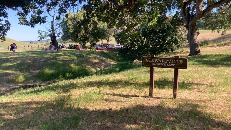 Backpack camp with grassy areas, trees, and people in the background at Black Diamond Mines Regional Preserve, California