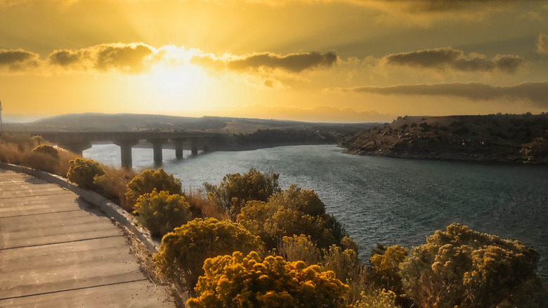 The sun sets over a bridge and the lake shore at Starvation Reservoir in Utah.