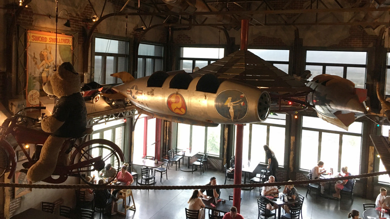 Inside of Strap Tank Brewery in Lehi, Utah with patrons sitting at tables below eclectic decor.