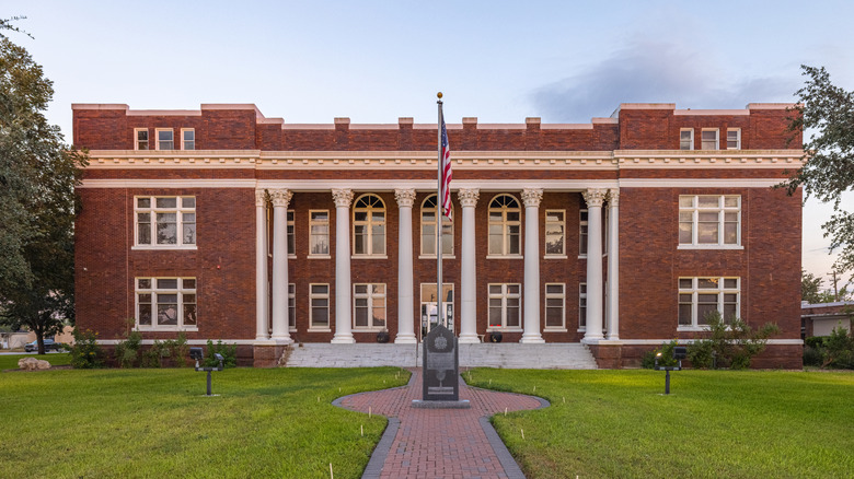 Red brick courthouse with white columns and blue sky in George West, Texas