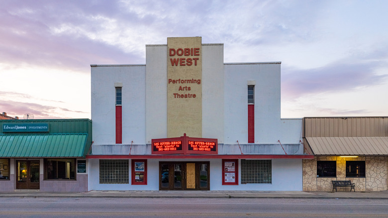Geometric white facade with red writing "Dobie West Performing Arts Theatre" in George West, Texas