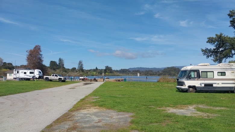 The grassy campground at Pinto Lake City Park overlooking the water and fishing piers.