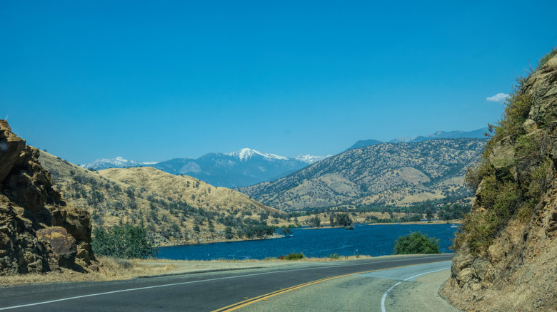 An open asphalt road leads into Woodlake, CA through sparse mountains