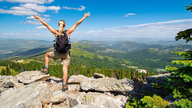 A hiker holding their arms up at a summit in Mount Spokane State Park