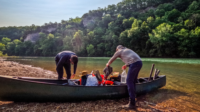 Two people packing up a canoe along the shoreline of the Buffalo National Scenic River