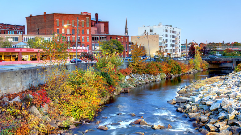 Historic buildings and a flowing river with rocks and foliage in Downtown Fitchburg, Massachusetts.