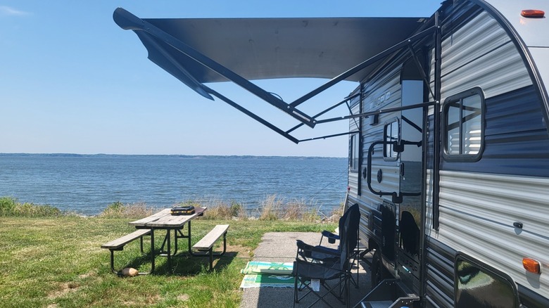 A picnic table and chairs outside a caravan on the edge of the lake at Wayne Fitzgerrell State Recreation Area.