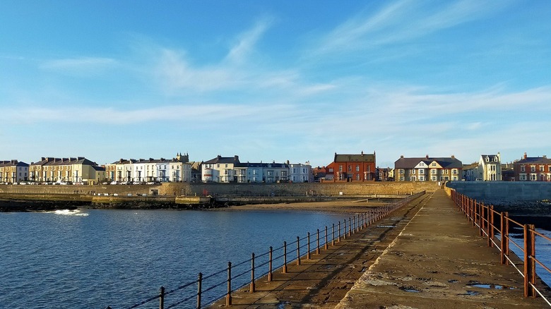 A pier in Hartlepool leads toward a seawall lined with two- and three-story buildings